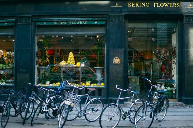 several assorted color bikes parked in front of bering flowers facade